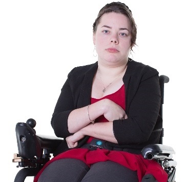 A woman in a wheelchair looking upset, with her arms crossed.