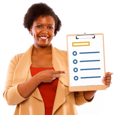 A woman is smiling , holding up a list and pointing at it with her other hand.